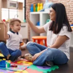 A support worker celebrating a win with a young child during a play-based therapy session, reinforcing progress with positive encouragement.
