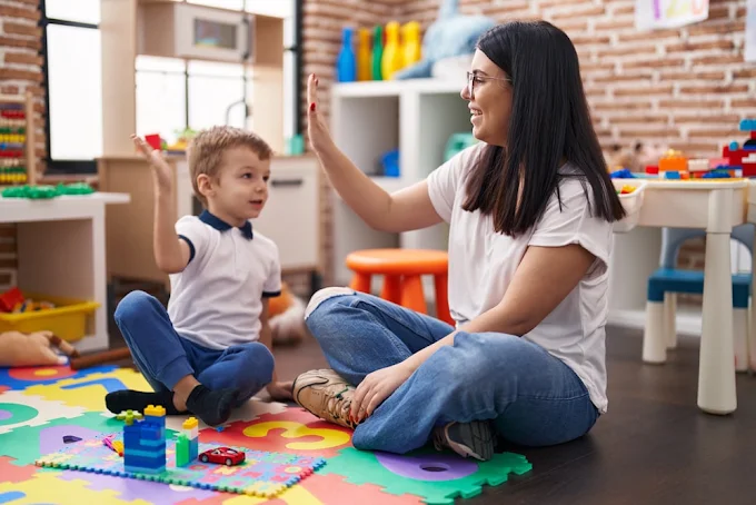 A support worker celebrating a win with a young child during a play-based therapy session, reinforcing progress with positive encouragement.